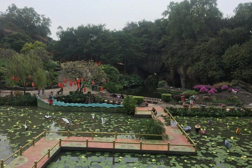 A pond with lily pads, a wooden bridge, and a tree with pink flowers. 3
