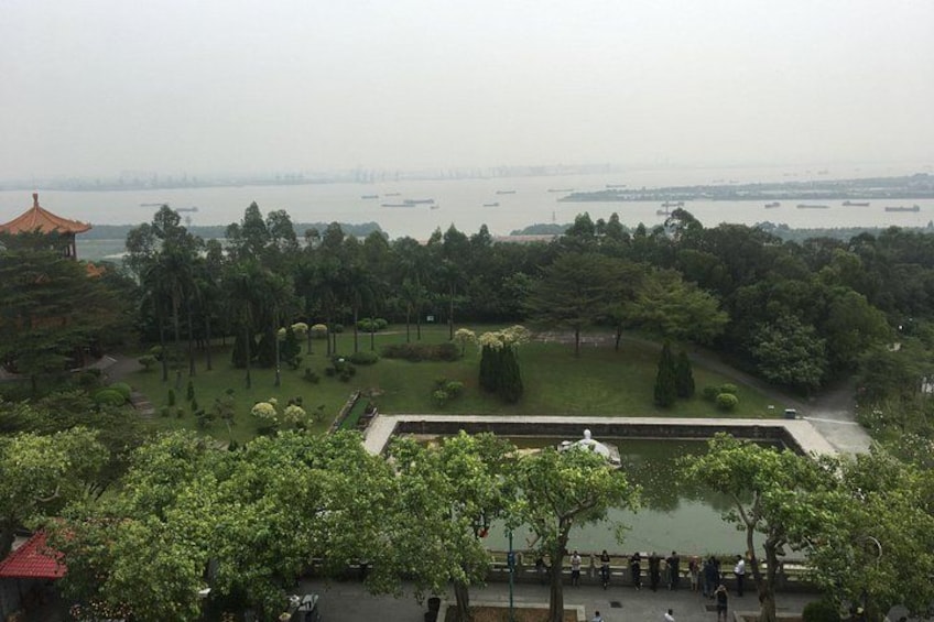 A park with a pond, trees, and a distant view of a body of water with boats. 4