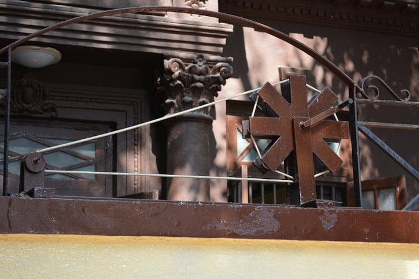 A metal gate with a star-shaped design, a potted plant, and a building facade in the background. 5