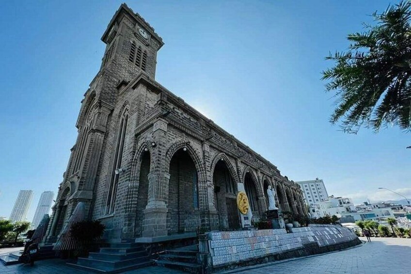 A large, historic stone building with a clock tower, arched windows, and a prominent entrance. 2