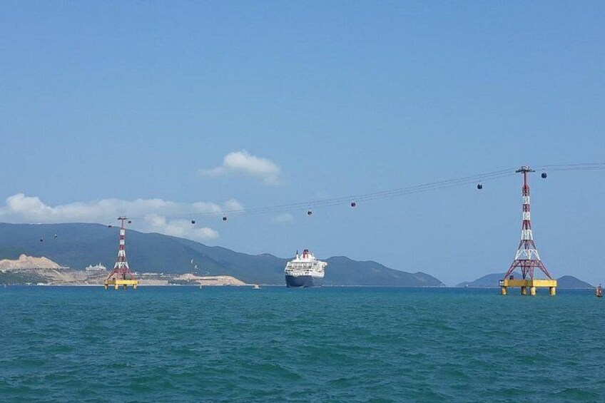 A cruise ship, a lighthouse, and a cable car system in a coastal area. 4