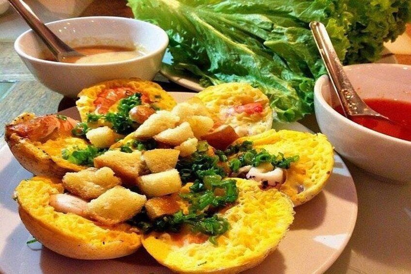 A plate of food with breaded items, possibly chicken, garnished with herbs, and accompanied by a bowl of sauce and a side of lettuce. 2