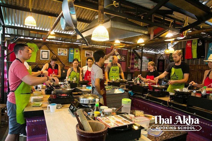 Une école de cuisine où des étudiants préparent des plats, avec des postes de cuisson et des ustensiles de cuisine à disposition. 3