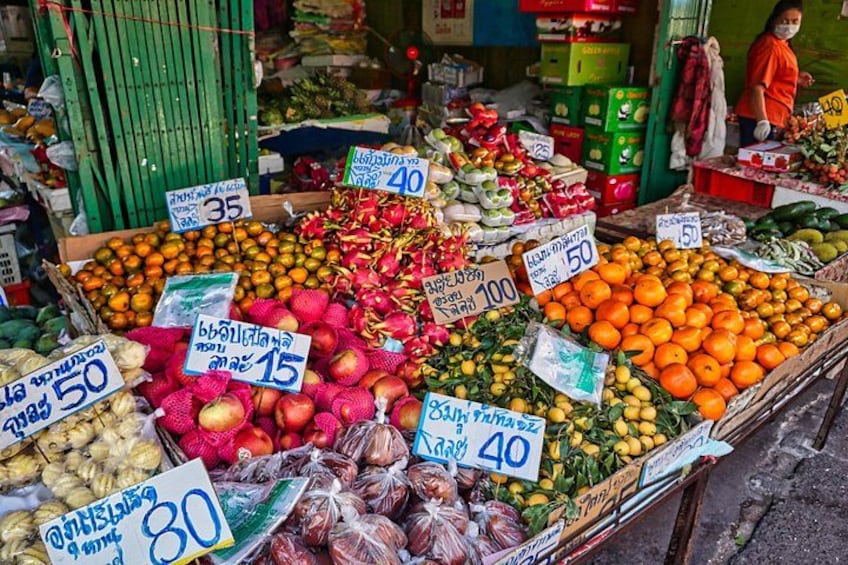 Un étal de marché proposant une variété de fruits et de légumes, notamment des oranges, des fruits du dragon et des citrons, avec des étiquettes indiquant les prix. 5