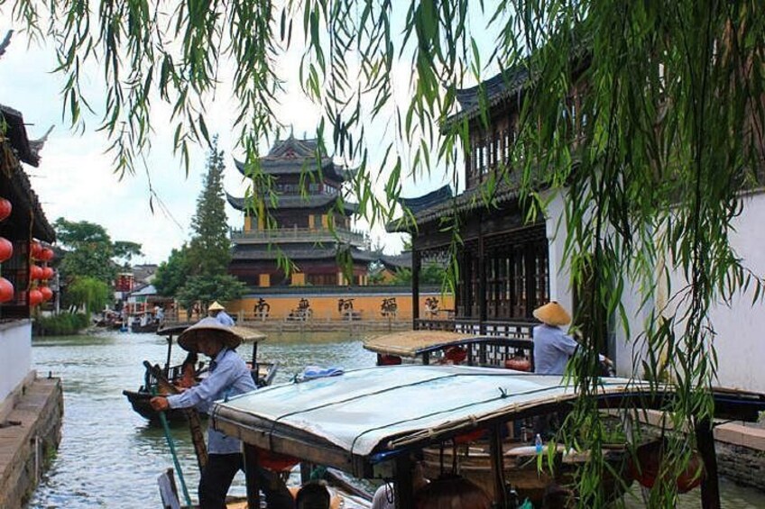 Een traditionele Chinese waterweg met bootjes, mensen in rieten hoeden en een pagode op de achtergrond. 2