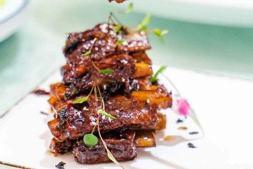 En rätt bestående av glaserat kött och grönsaker, serverad på en tallrik. 3