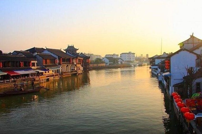 A river with traditional buildings on the banks, a boat docked on the left, and a clear sky. 3