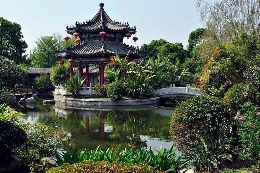 A traditional Chinese pavilion with a pond, surrounded by lush greenery and a stone bridge. 3