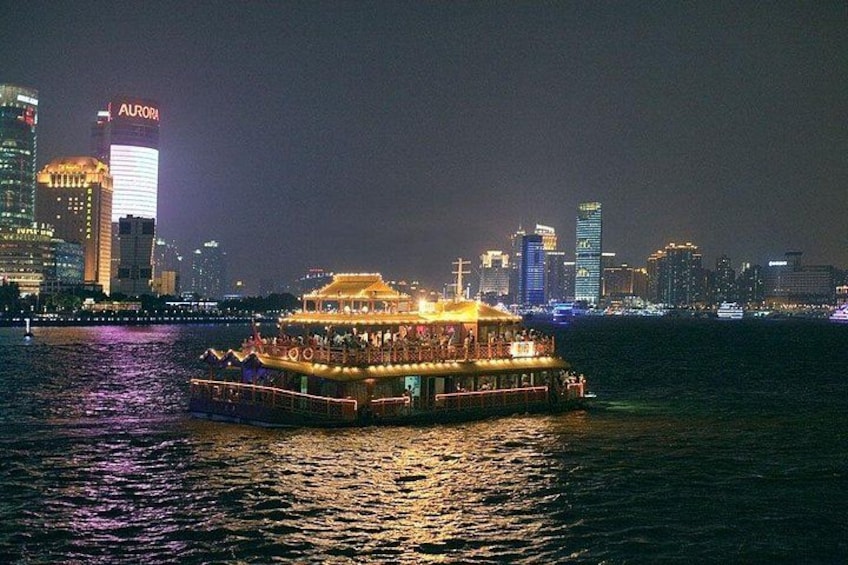 Ein hell erleuchtetes Schiff mit mehreren Decks, im Hintergrund ein Stadtpanorama und Spiegelungen auf dem Wasser. 3