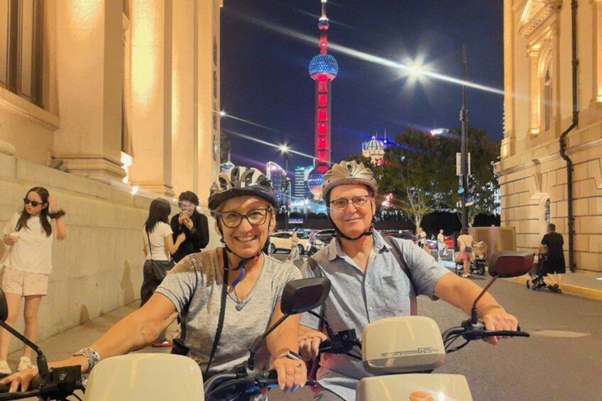 A person on a scooter with a helmet, another person beside them, and a tower in the background. 4
