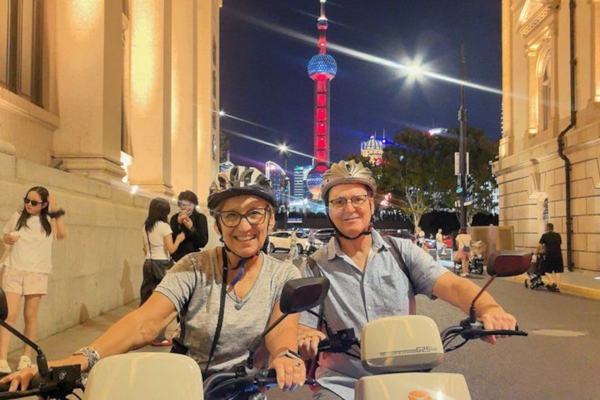 A person on a scooter with a helmet, another person beside them, and a tower in the background. 3