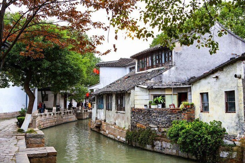 A traditional canal-side building with a stone bridge, surrounded by trees and water. 1