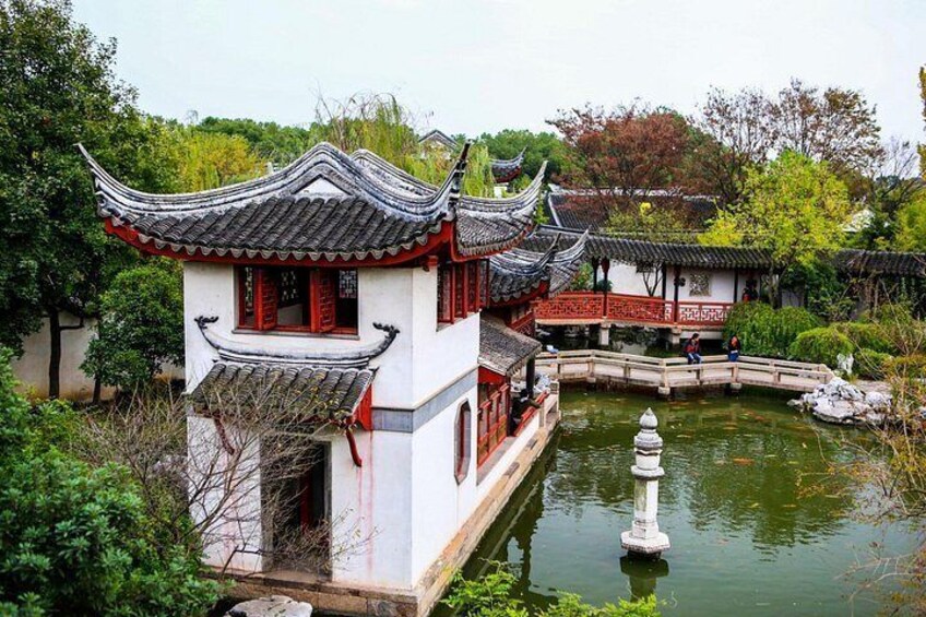 A traditional Chinese building with a tiled roof, a pond with a stone lantern, and a bridge. 4