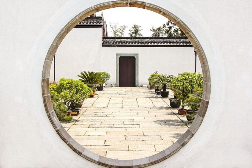 A courtyard with a stone pathway leading to a door, surrounded by potted plants. 2