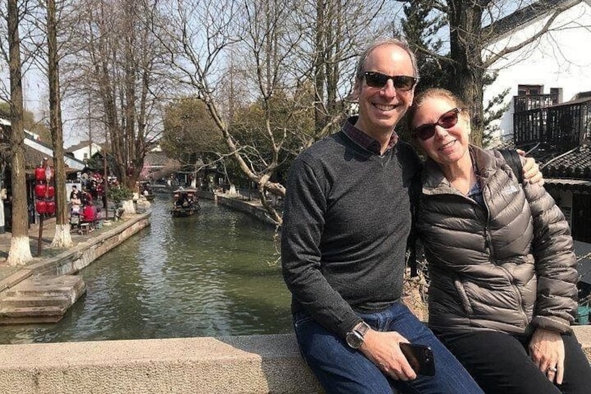 A couple sitting by a canal with boats and traditional buildings in the background. 3