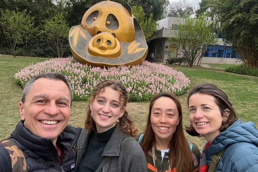 Un grupo de personas frente a una escultura que muestra un oso y un arreglo floral. 3