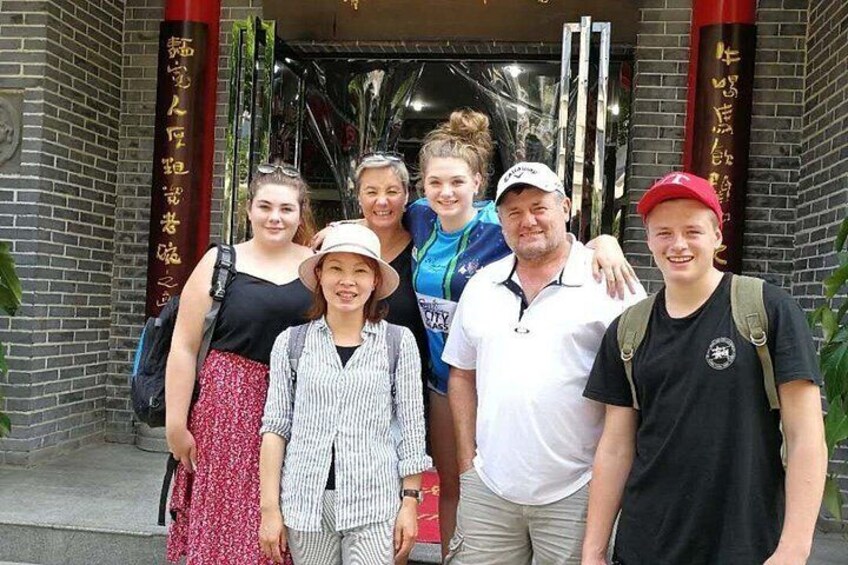 A group of people standing in front of a building with traditional Chinese architecture, including a red pillar and golden Chinese characters. 1