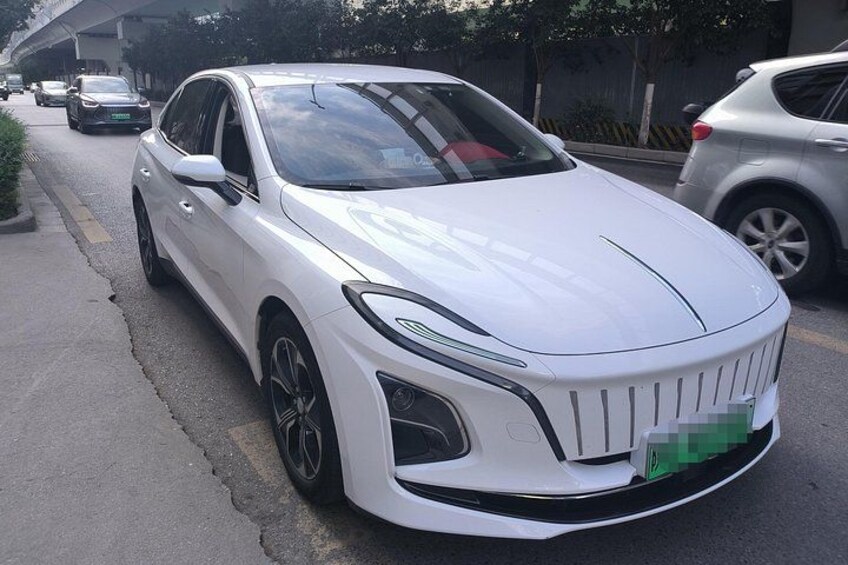 A white car parked on a street with other vehicles in the background. 2