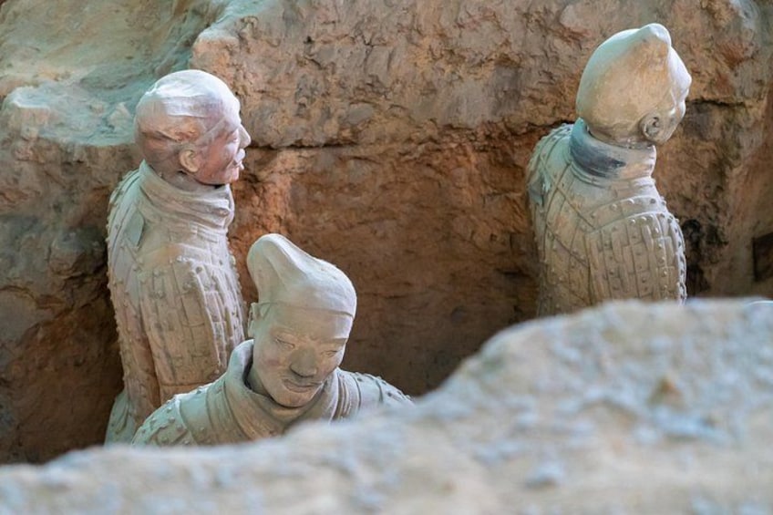 Terracotta sculptures of a seated man and two standing figures in a cave. 1