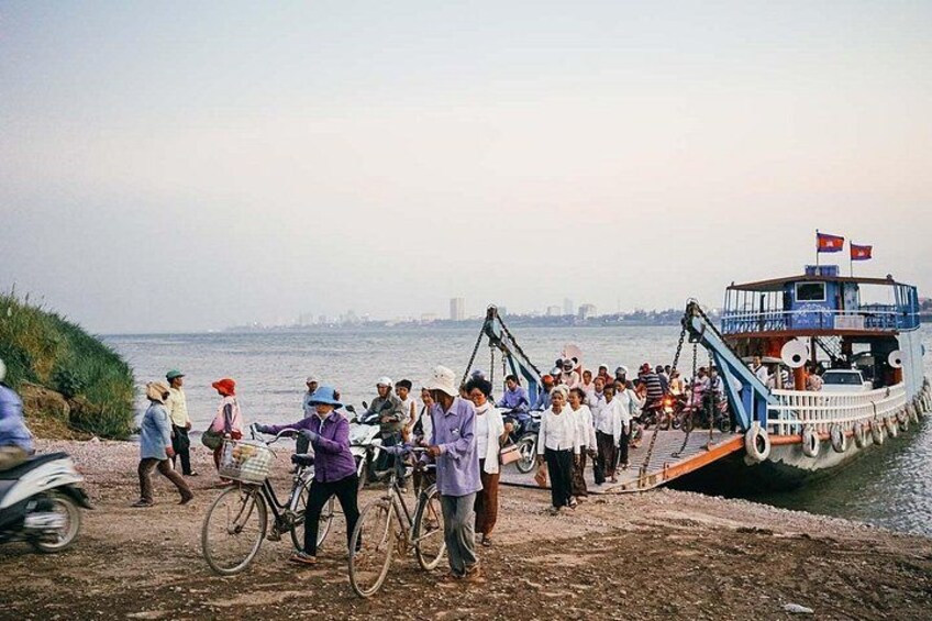 A group of people on a dock by a body of water, with a boat in the background. 3
