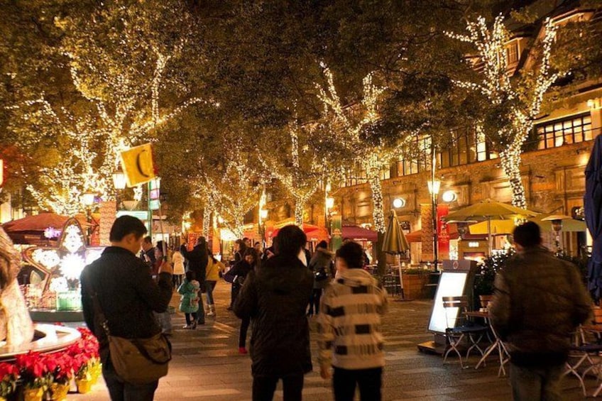 A crowded street at night with illuminated trees and buildings. 1