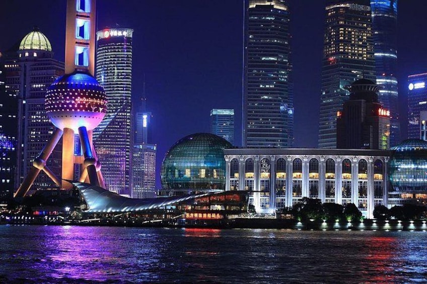 A cityscape at night with illuminated buildings, a distinctive spherical structure, and a bridge. 2
