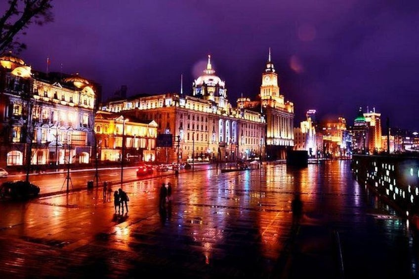 A nighttime cityscape with illuminated buildings and a reflective water surface. 2