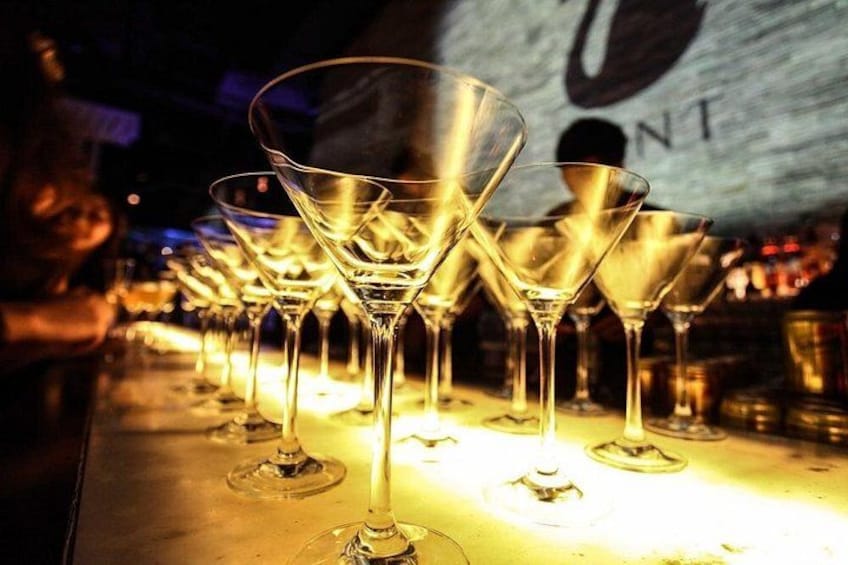 A bar with multiple martini glasses lined up on a counter. 5