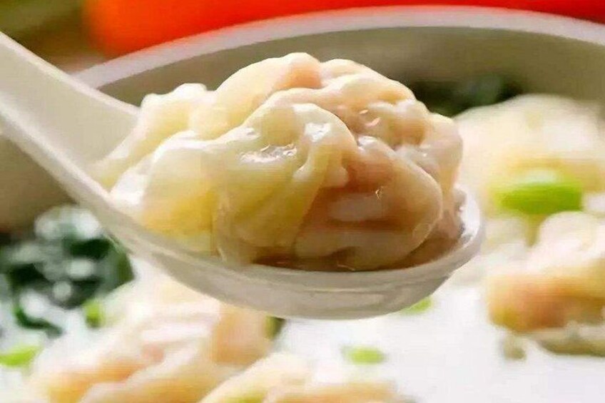 En sked full av dumplings med en krämig sås, eventuellt serverat i en skål. 2