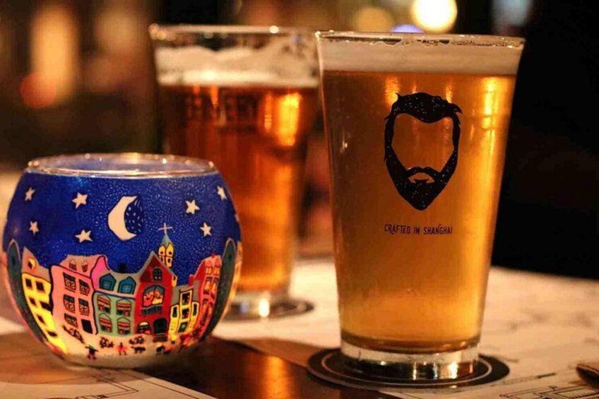 A beer glass with a beard logo and a can with a colorful cityscape design. 3