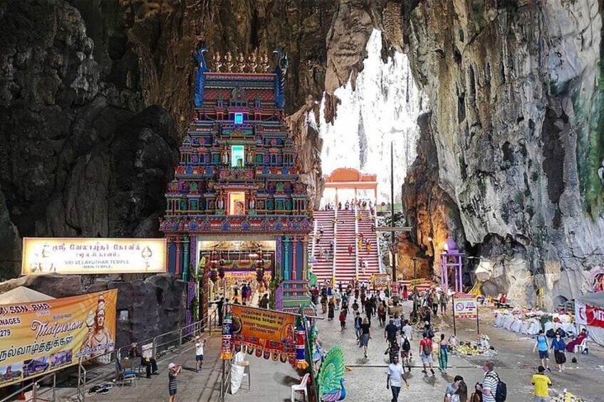 A cave temple with intricate carvings and a large crowd of visitors. 5