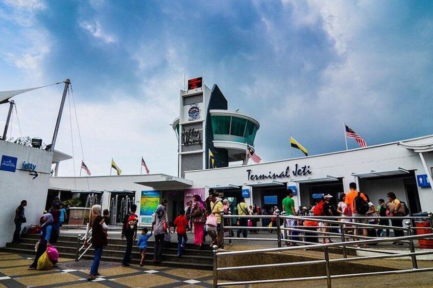 A busy terminal with people boarding a ship, a control tower, and multiple flags. 3