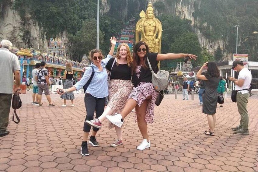 A group of people posing in front of a large golden statue in a temple complex. 1