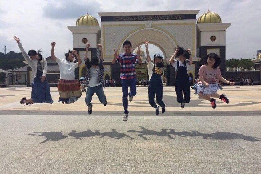 A group of people jumping in front of a large building with domes. 1
