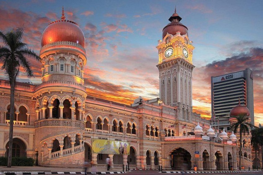A grand building with domes and a clock tower, surrounded by palm trees and a sunset sky. 3