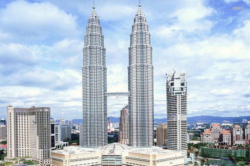 The Petronas Twin Towers in Kuala Lumpur, Malaysia, surrounded by other high-rise buildings and a partly cloudy sky. 2