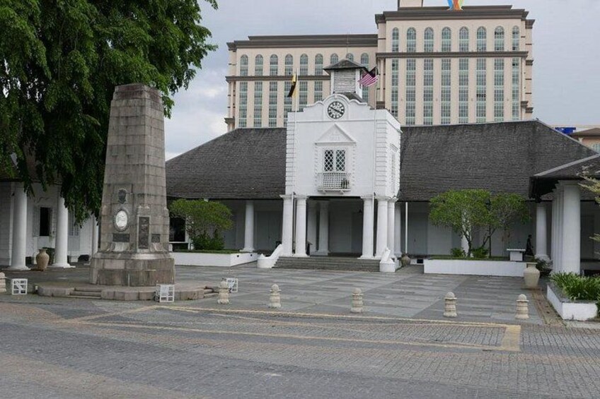 A building with a clock tower, a flag, and a large tree in front. 4