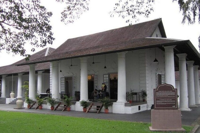 A colonial-style building with a covered porch, columns, and a signboard. 5