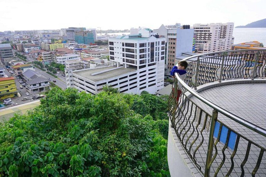 A cityscape with buildings, a parking garage, and a person on a balcony. 2