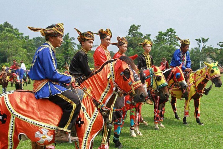 People in traditional costumes riding decorated horses in a grassy field. 1