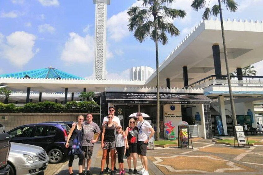 A group of people posing in front of a modern building with a white facade and a blue roof. 4