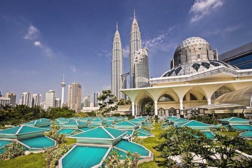 A resort with multiple swimming pools, a large dome structure, and the Petronas Towers in the background. 1