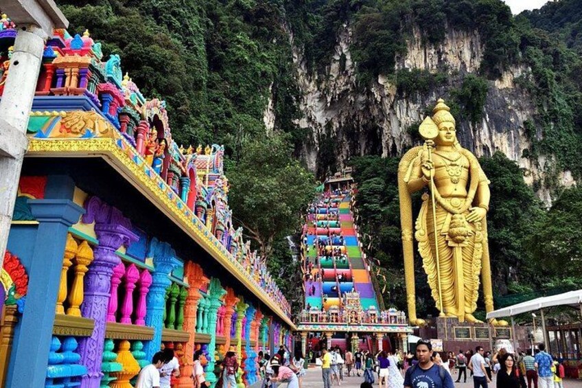 A large golden statue, colorful temple architecture, and a steep staircase. 3