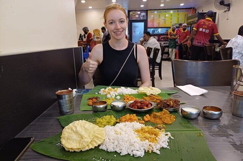 A person sitting at a table with various dishes including rice, curry, and other Indian cuisine. 4