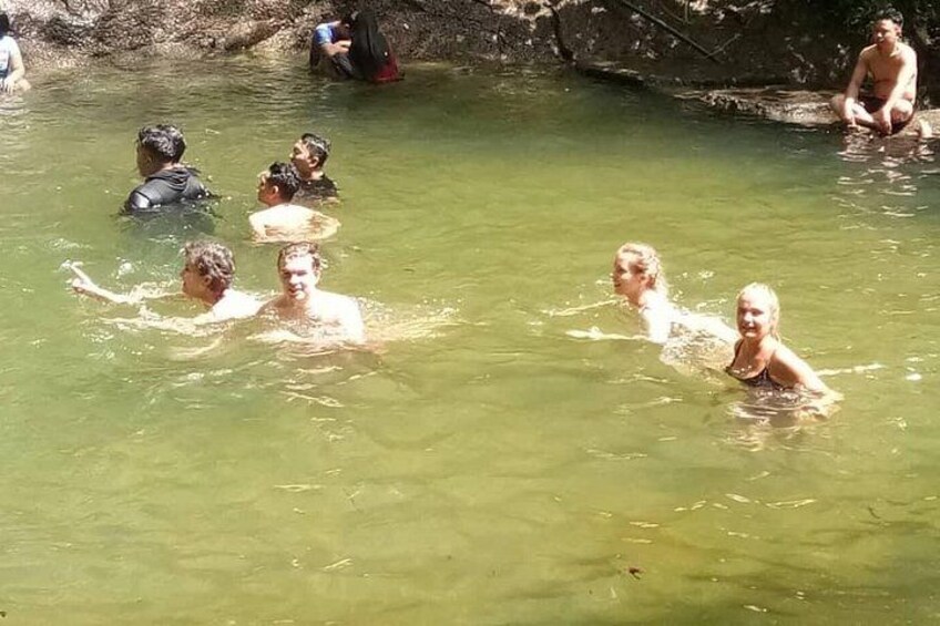 People swimming in a natural water body surrounded by rocks. 4
