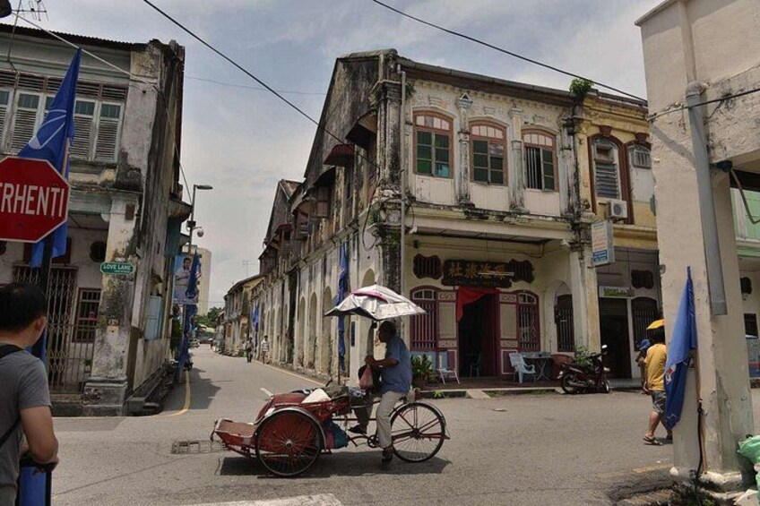 A street scene with a man riding a bicycle with a cart, buildings with signs, and a stop sign. 3