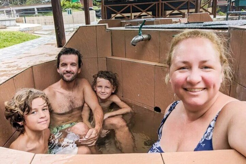 A family in a hot tub with a wooden deck and a metal faucet in the background. 1