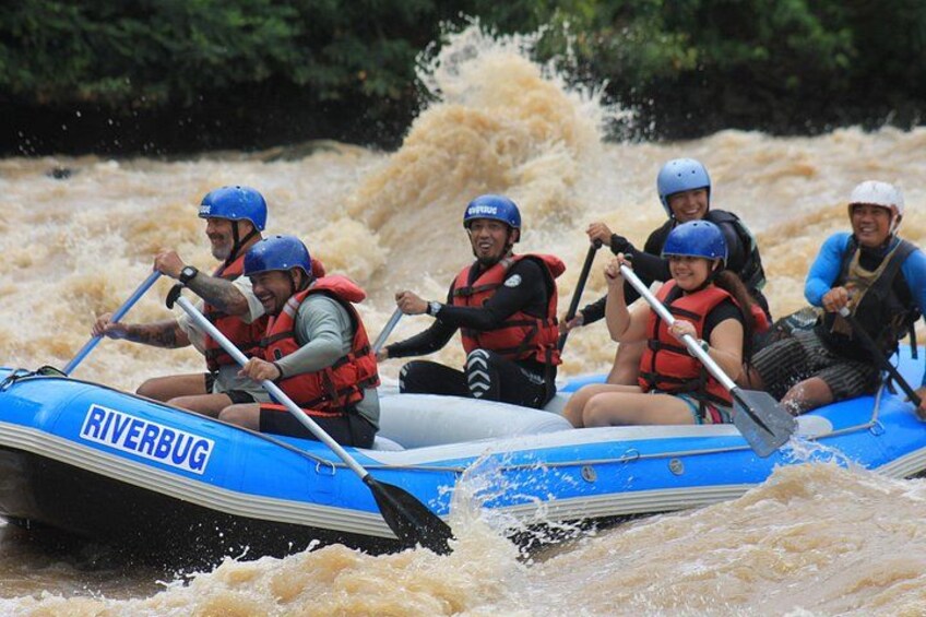 A group of people in a blue inflatable raft navigating through a river with rapids. 3
