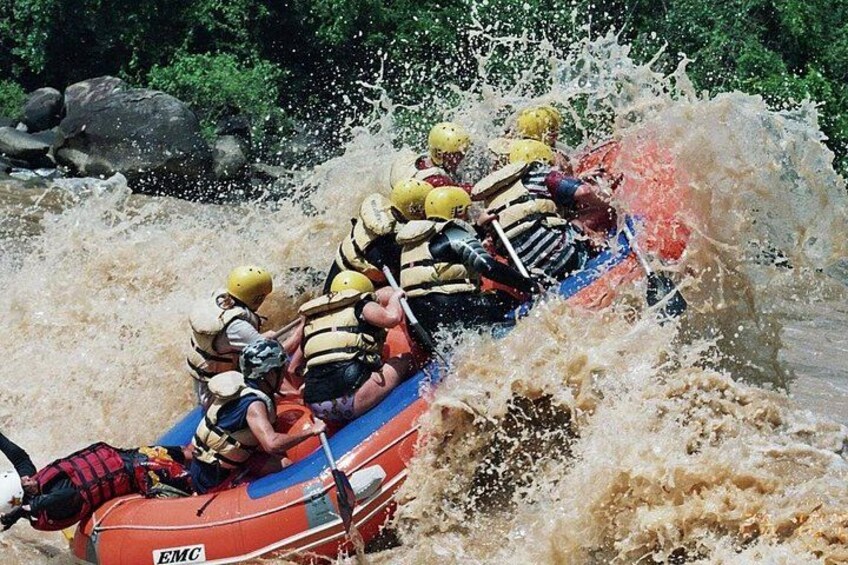 A group of people in a raft navigating through a turbulent river. 1
