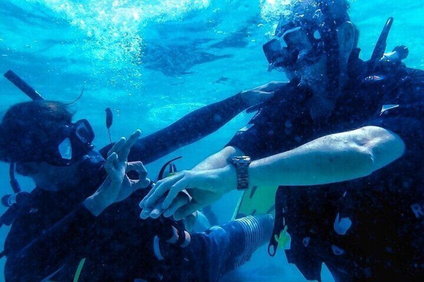 Two scuba divers underwater, wearing fins and masks, reaching out to each other. 2